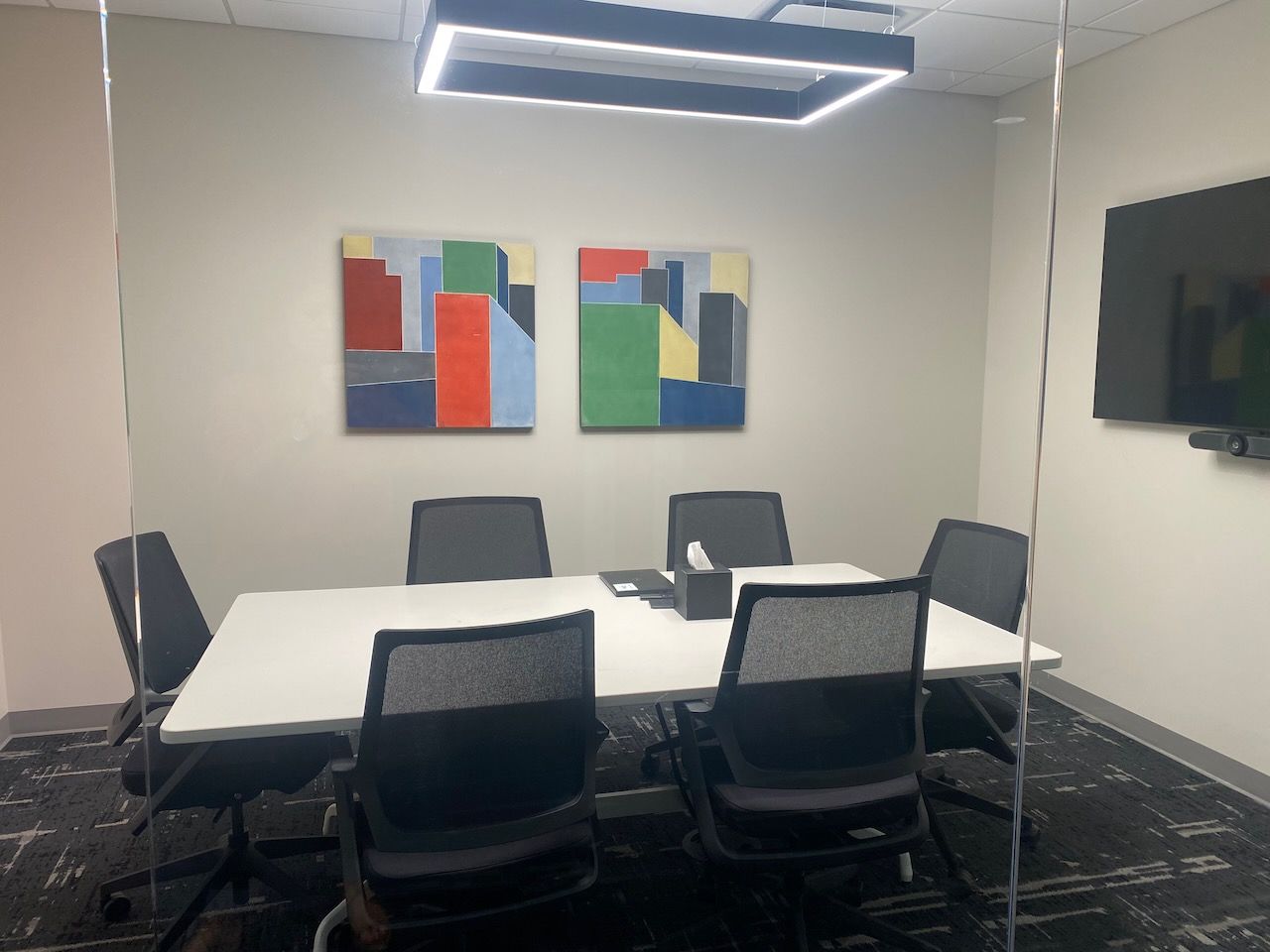 A conference room with a table and chairs and paintings on the wall.