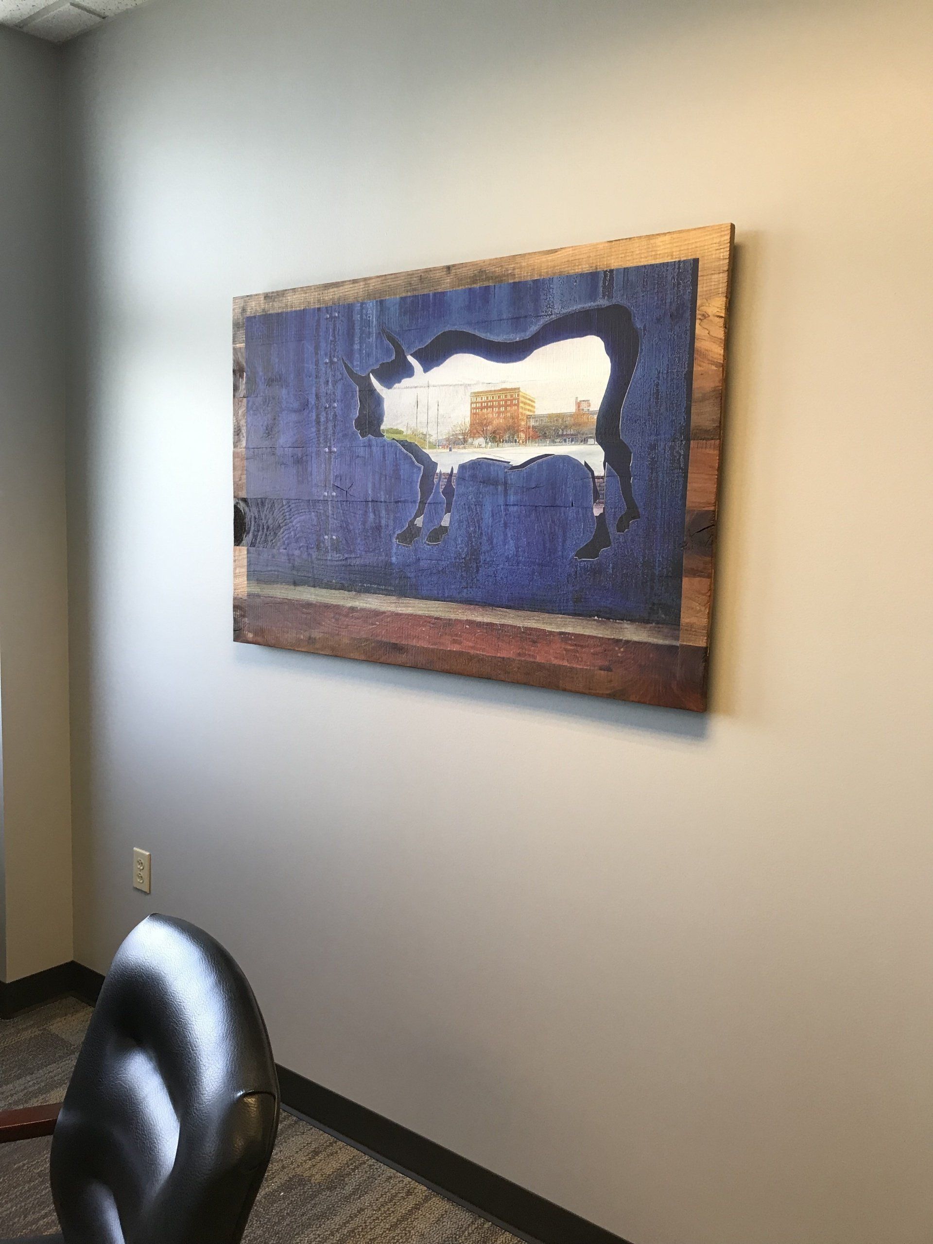 A large painting of a bull is hanging on a wall in a room.