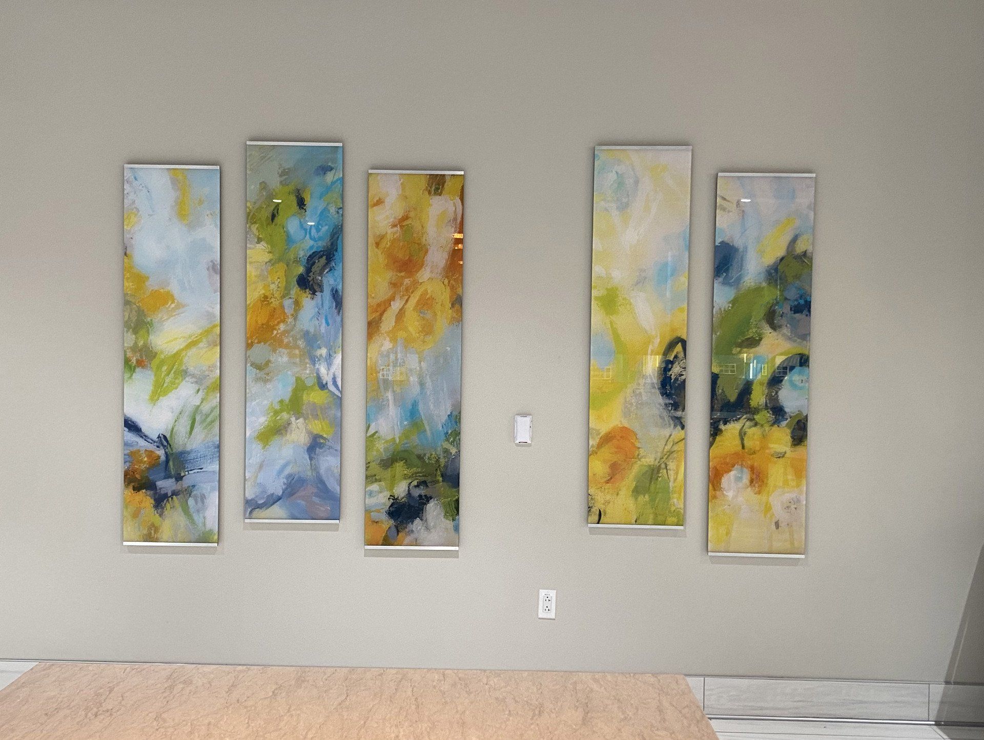 Four paintings are hanging on a wall in a room.