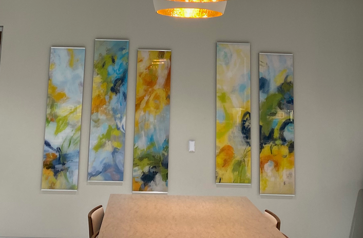 A dining room with a table and chairs and paintings on the wall.