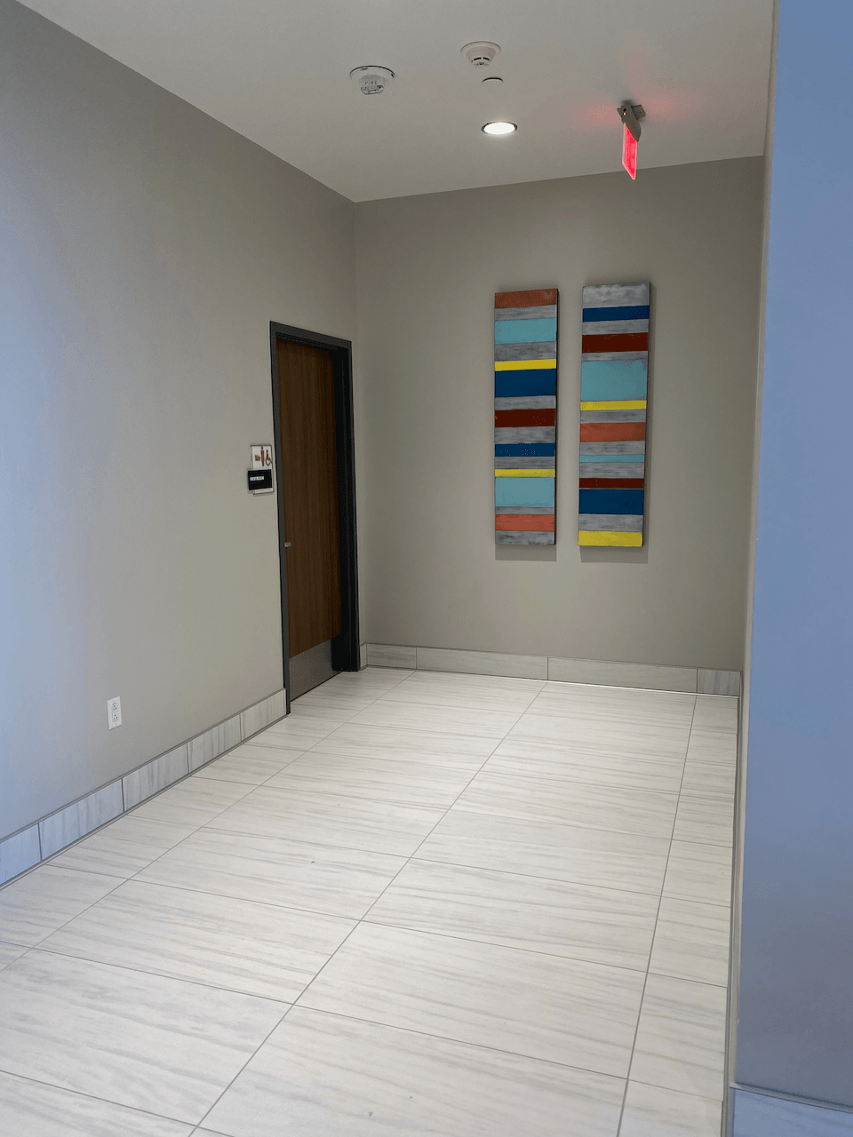 A hallway with a door and two paintings on the wall