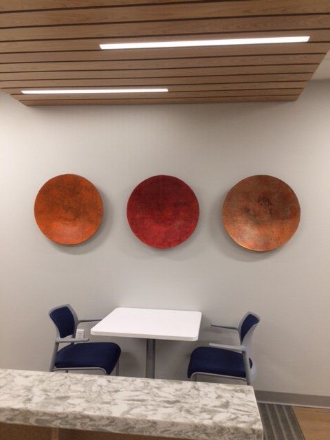 Three red plates are hanging on a wall above a table and chairs