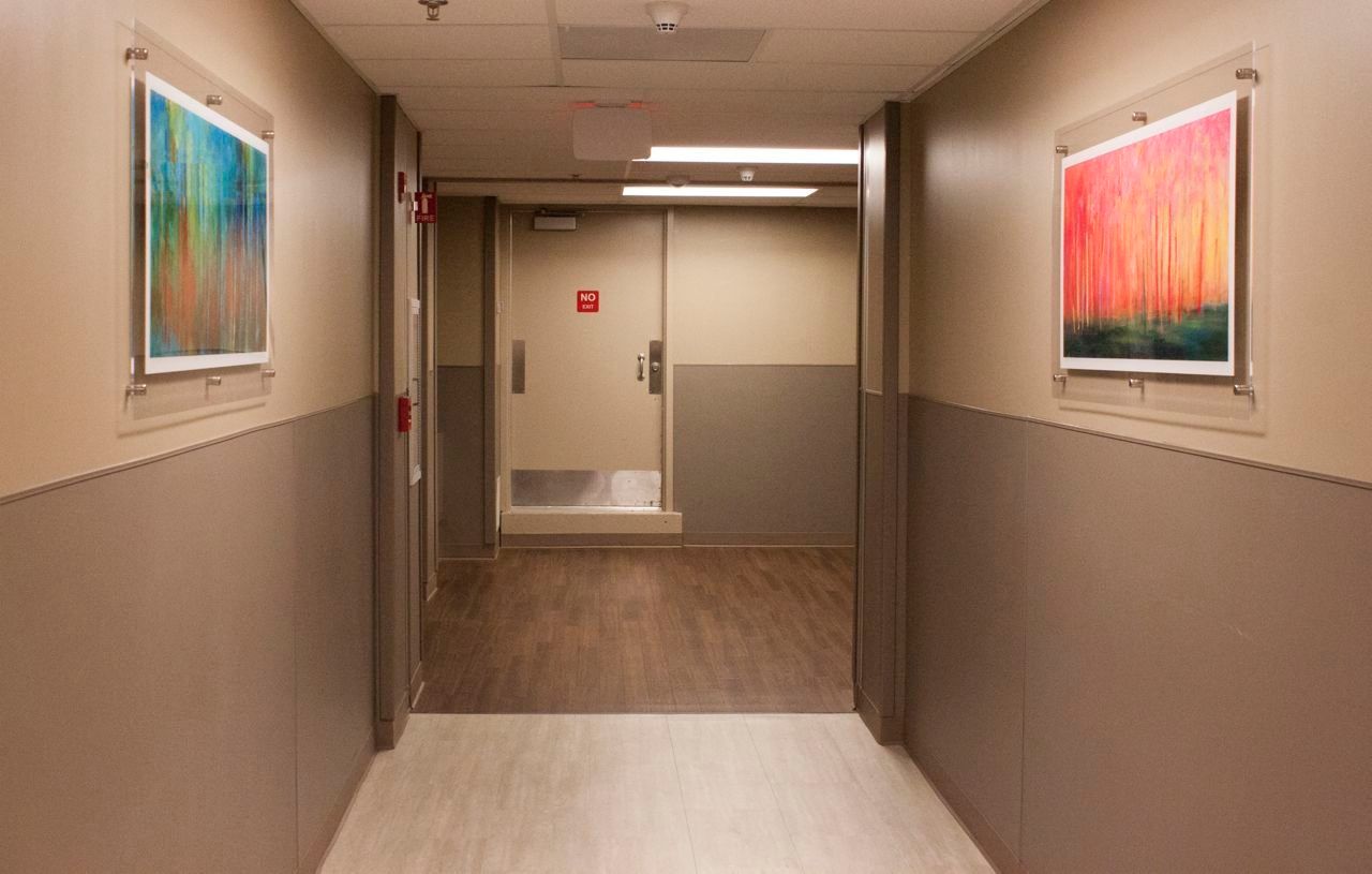 A hallway in a hospital with paintings on the wall.