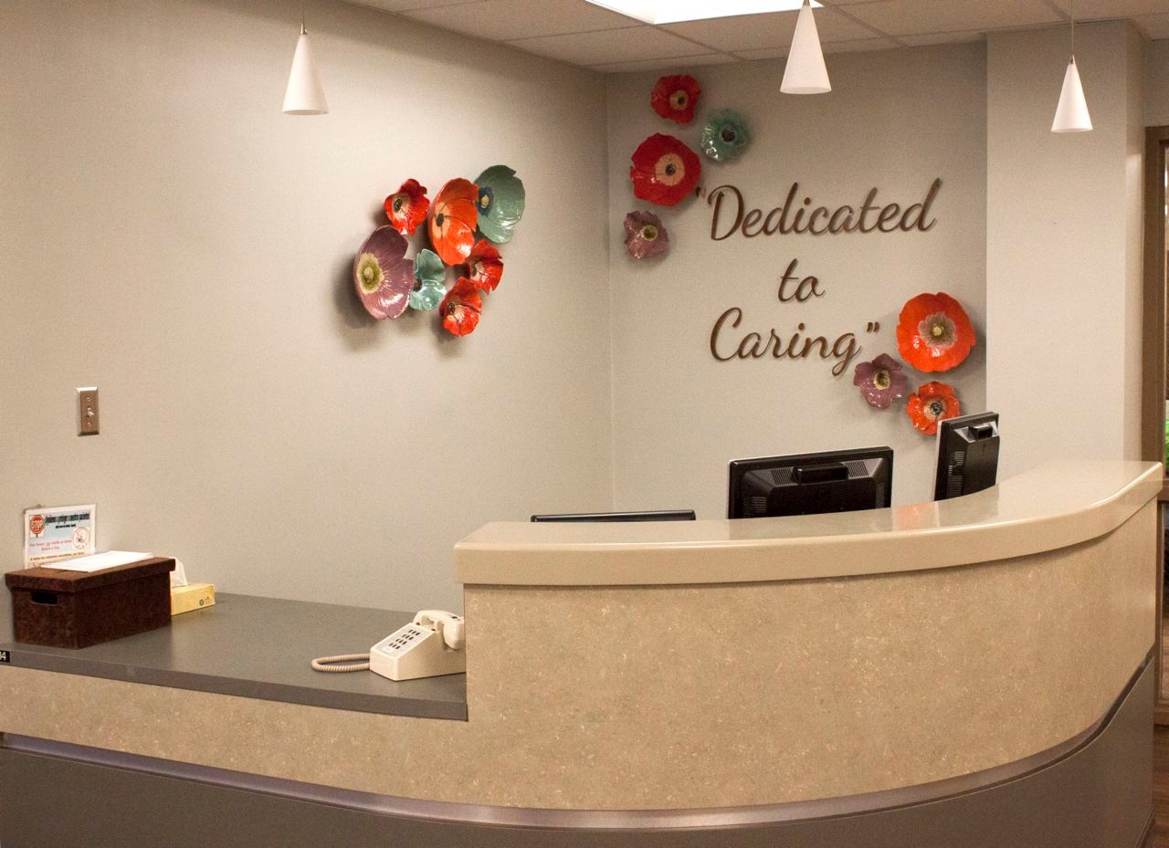 A reception desk with a sign on the wall that says dedicated to caring