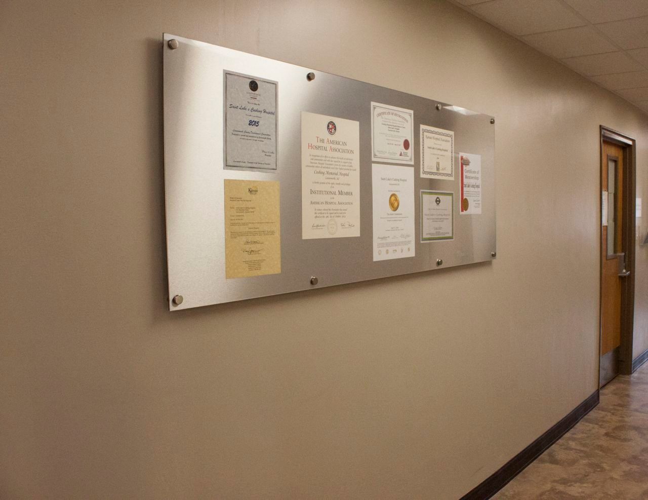 A bulletin board is hanging on a wall in a hallway.
