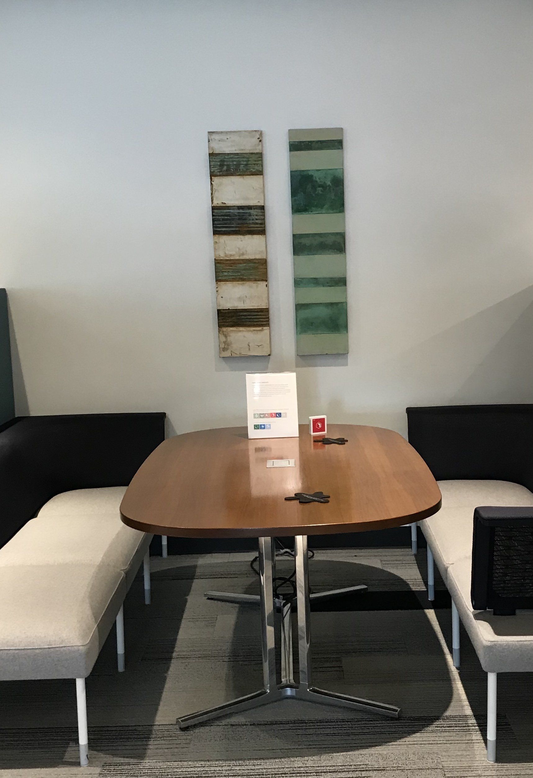 A room with a table and chairs and two paintings on the wall