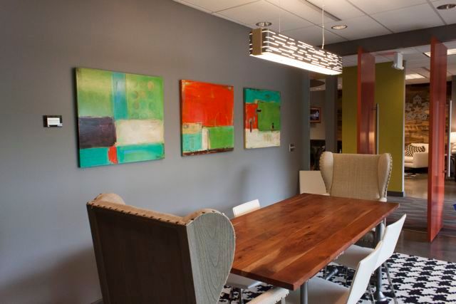 A dining room with a table and chairs and paintings on the wall