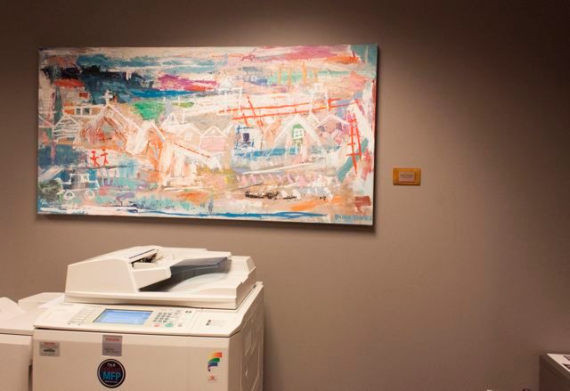 A large painting is hanging on a wall above a printer.