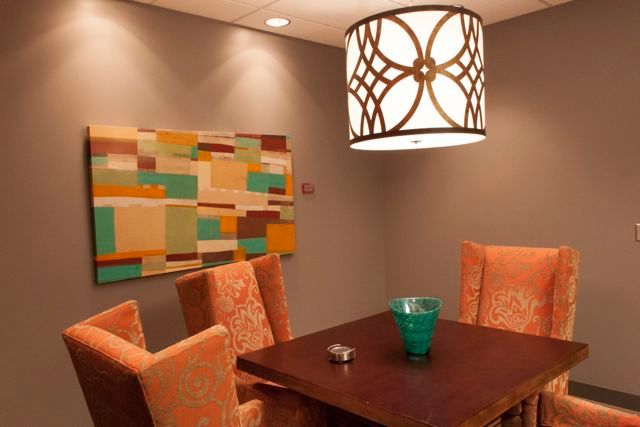 A dining room with a table and chairs and a painting on the wall