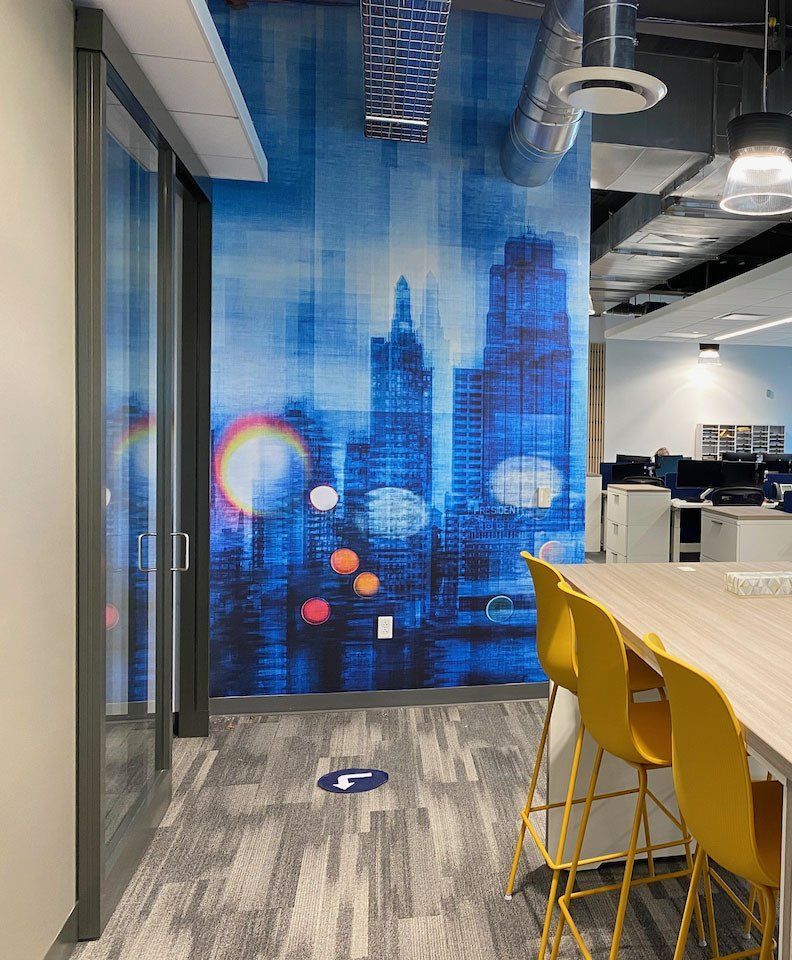 A room with a table and chairs and a wall with a picture of a city skyline.