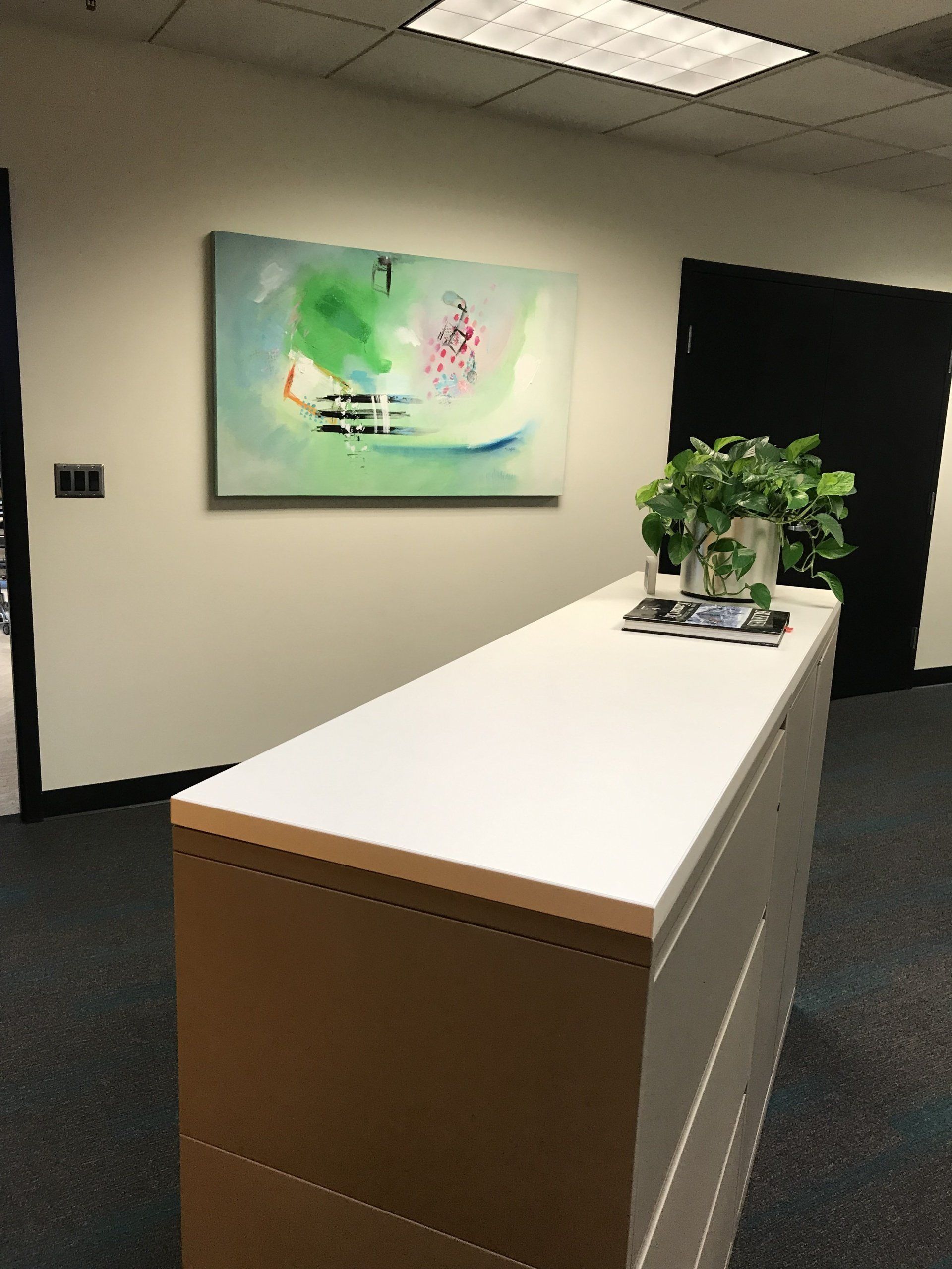 A long white counter in a room with a painting on the wall above it.