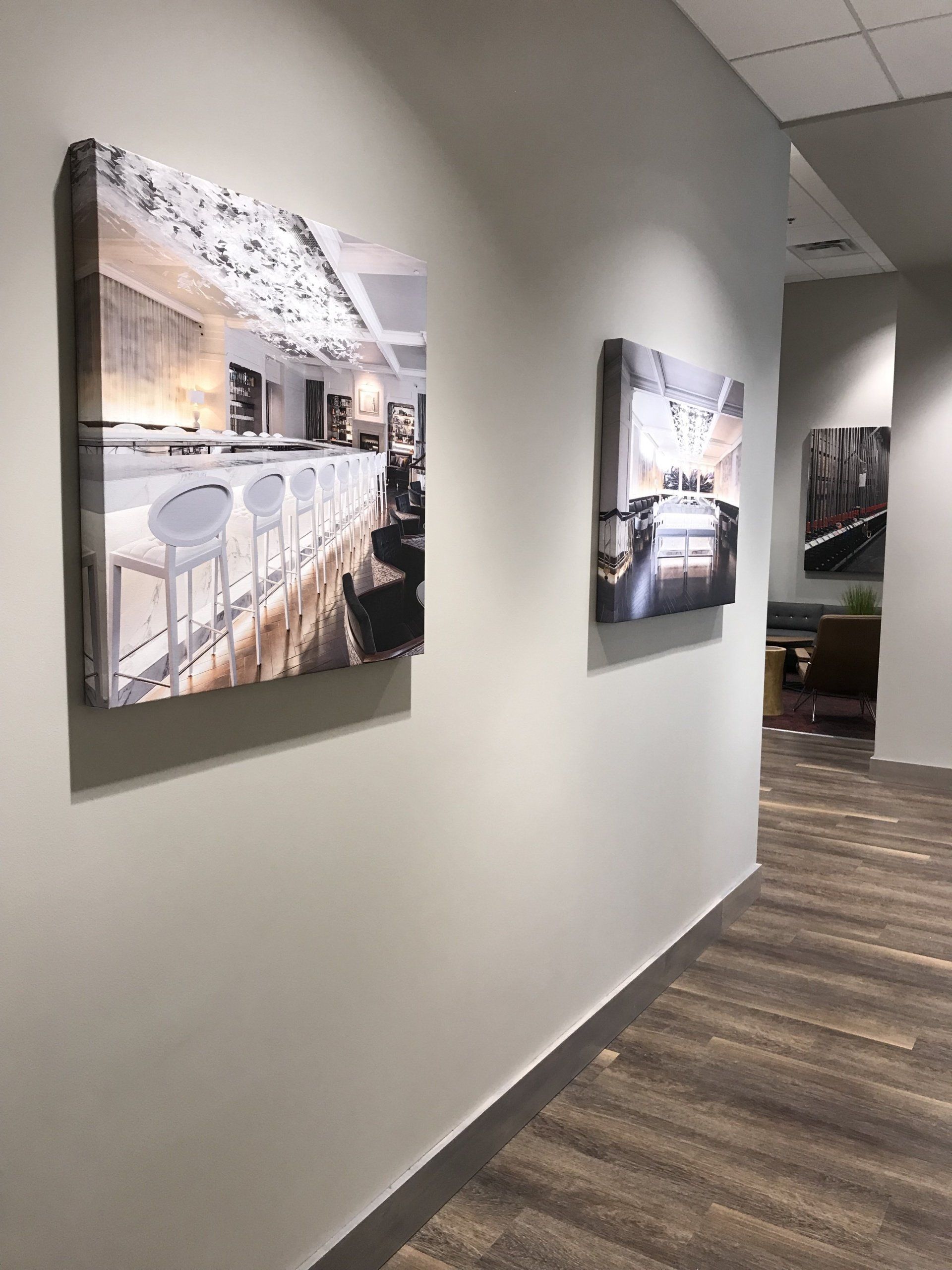 Two paintings are hanging on a wall in a hallway.