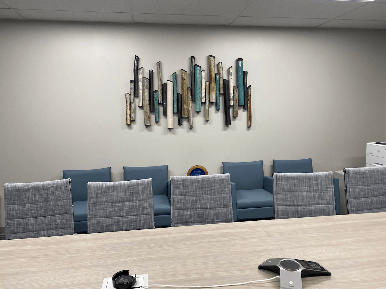 A conference room with a long table and chairs and a painting on the wall.