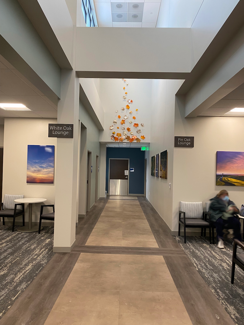 A long hallway with tables and chairs in a hospital.