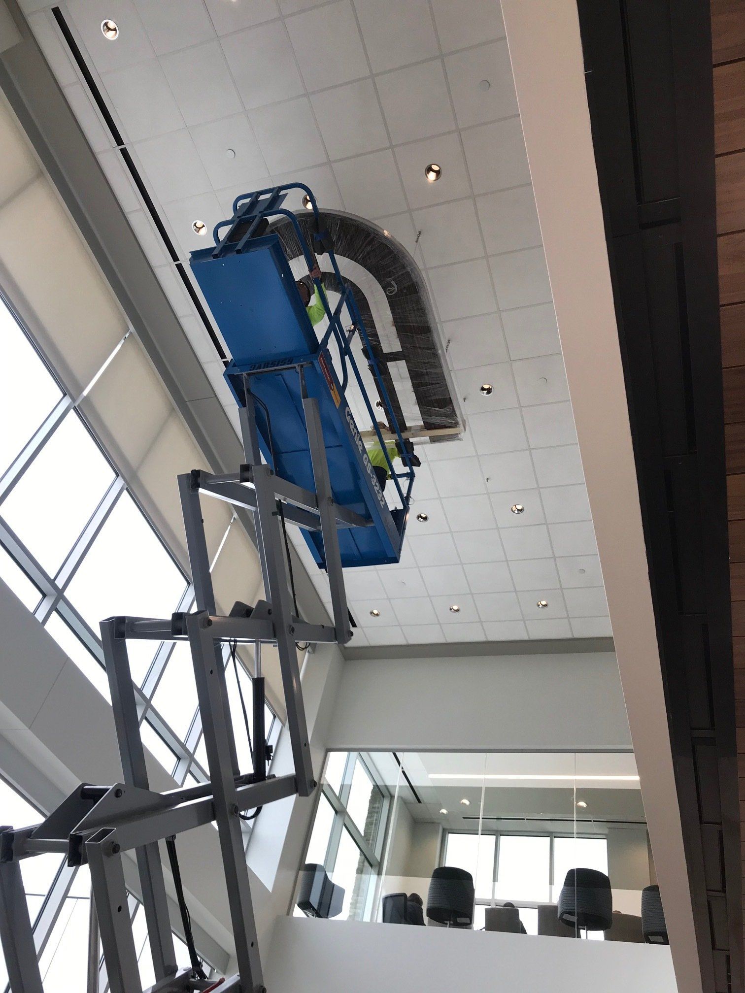 A man is working on the ceiling of a building with a lift.