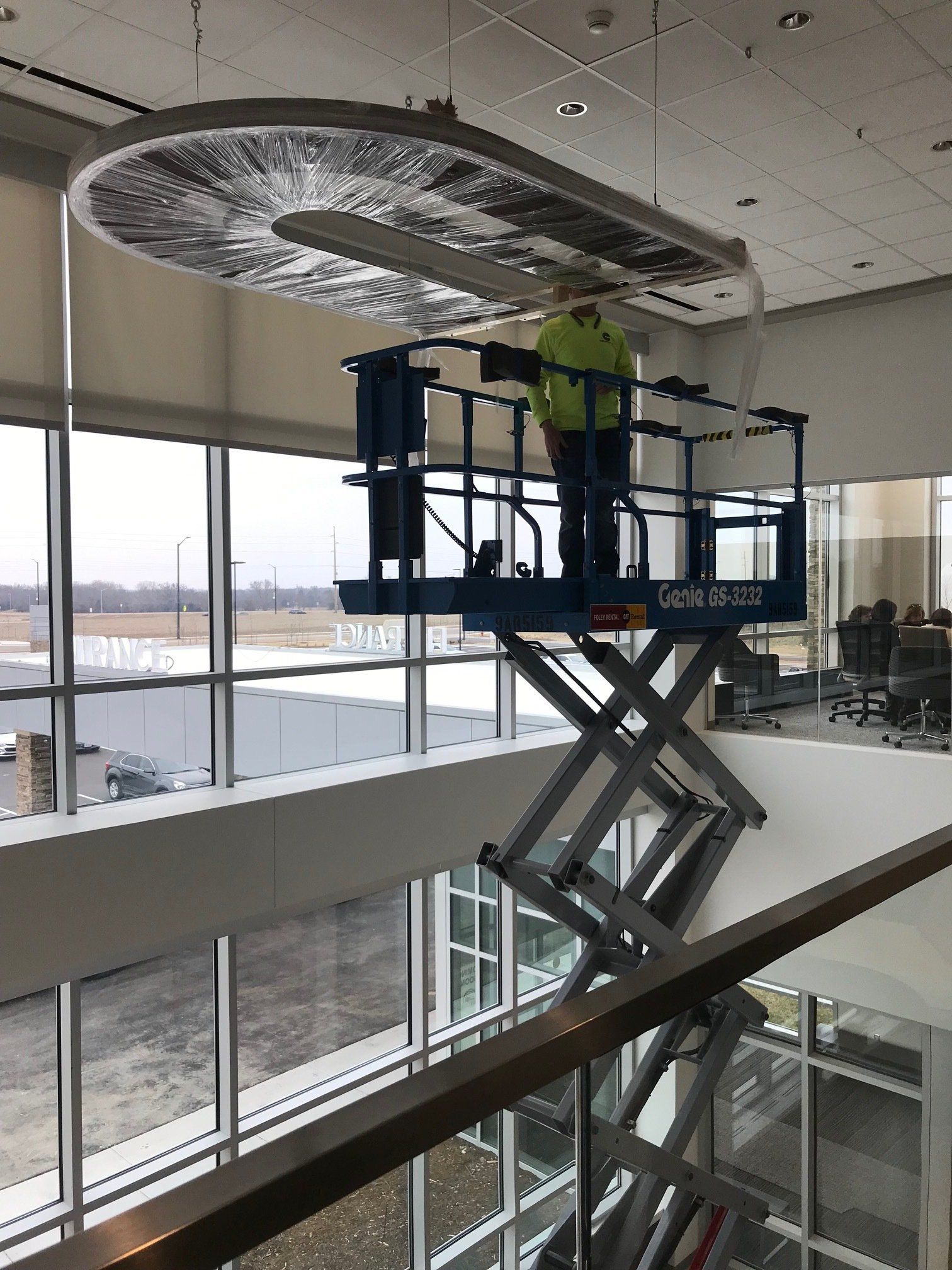 A man is standing on a scissor lift in a building.