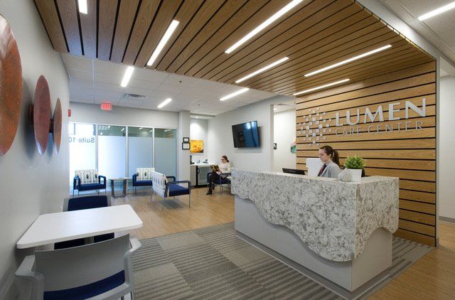 A woman is sitting at a desk in a room with a sign that says welcome