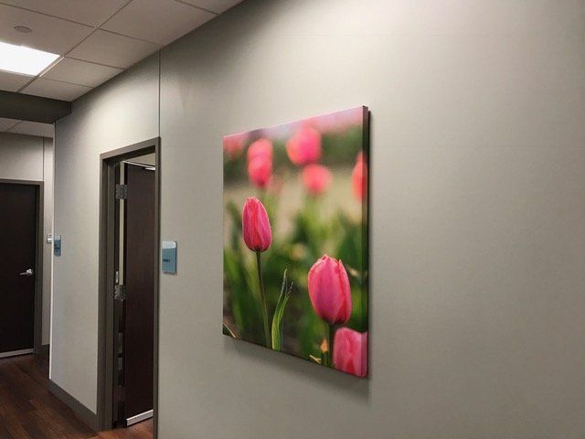 A painting of pink tulips is hanging on a wall in a hallway.