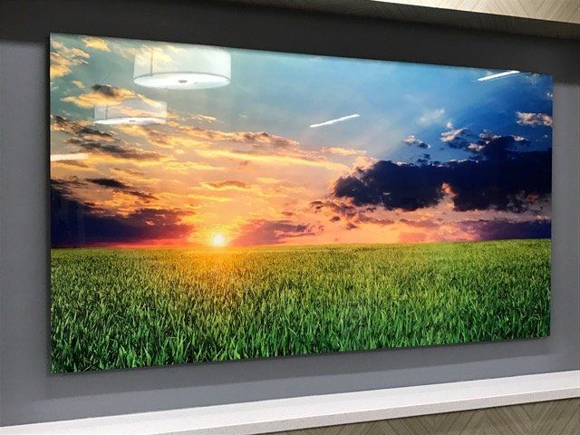 A large painting of a field with a sunset in the background
