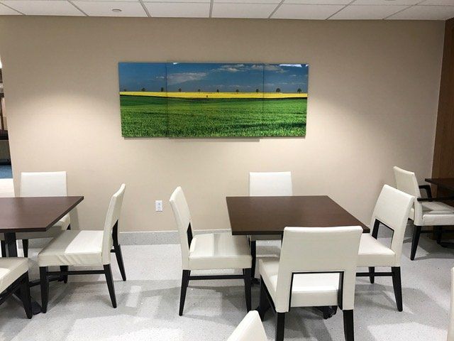 A room with tables and chairs and a painting on the wall