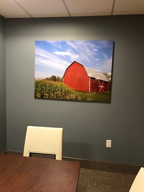 A picture of a red barn is hanging on a wall