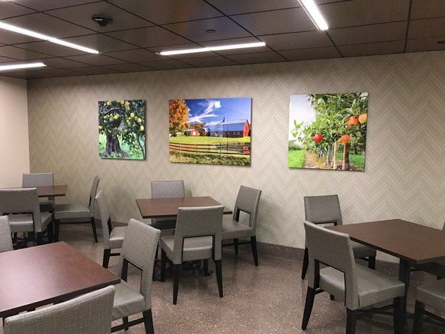 A dining room with tables and chairs and paintings on the wall