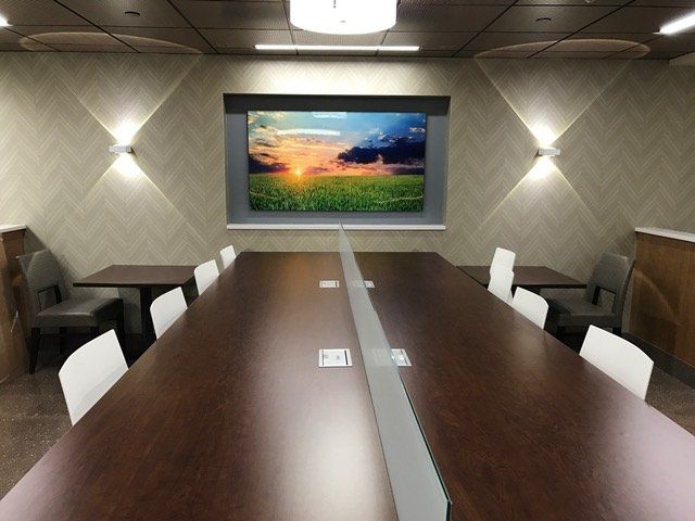 A conference room with tables and chairs and a large picture on the wall