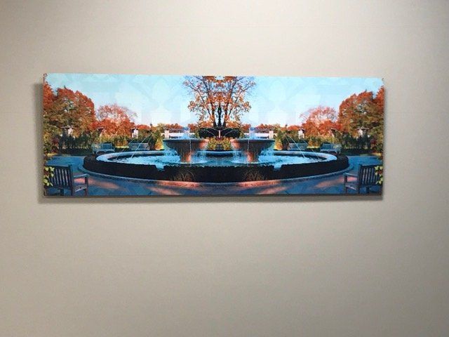 A painting of a fountain is hanging on a wall.