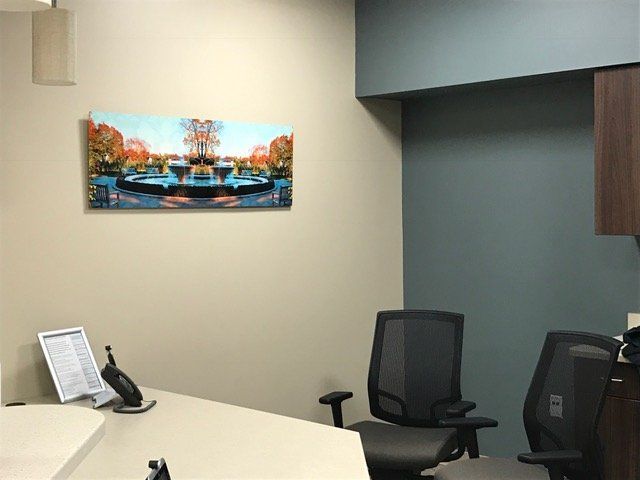 A painting of a fountain hangs above a desk in an office