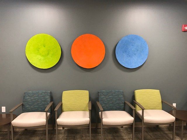 A row of chairs in a waiting room with three colorful circles on the wall