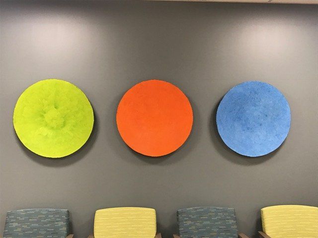 Three colorful circles are hanging on a wall above a row of chairs