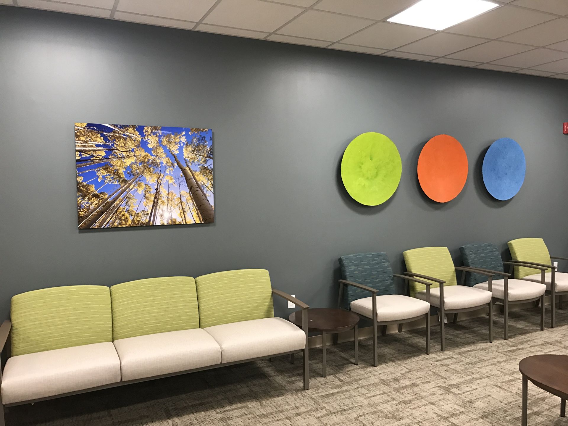 A waiting room with colorful chairs and a painting on the wall.