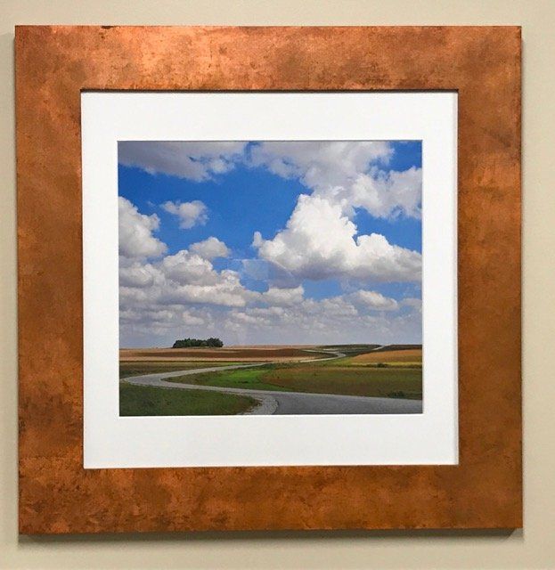 A picture in a copper frame shows a road going through a field