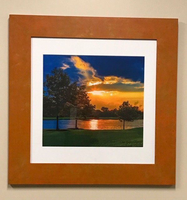 A framed picture of a sunset over a lake