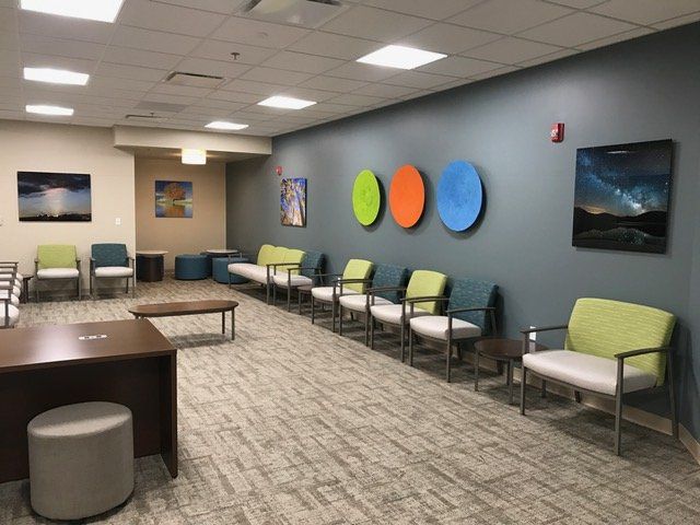 A waiting room with a row of chairs and a desk