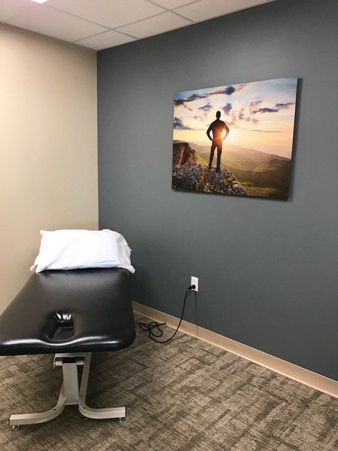 There is a picture of a man standing on top of a mountain on the wall above a table.