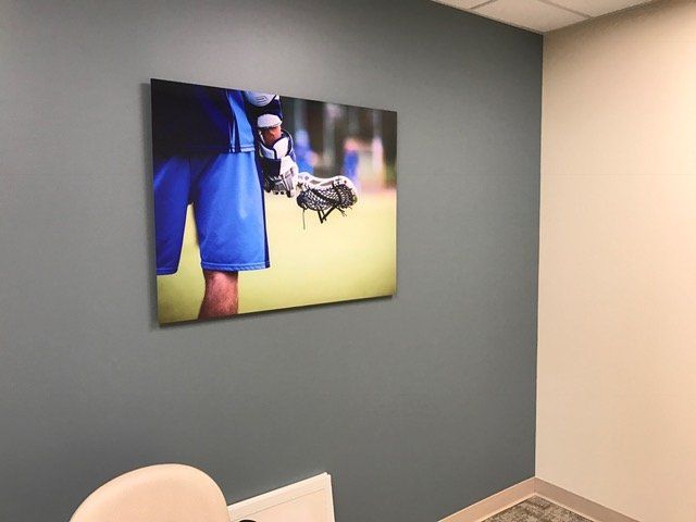 A picture of a person holding a baseball glove is hanging on a wall.