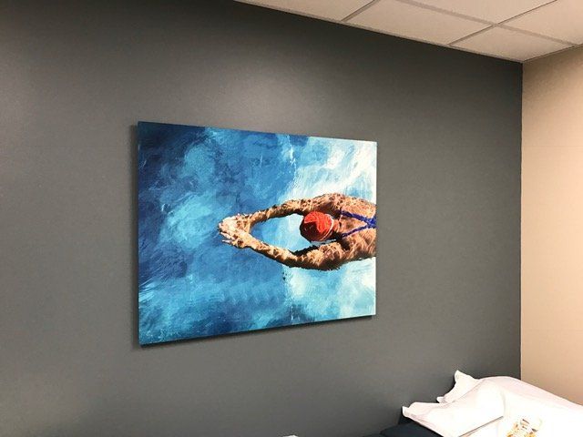 A painting of a person swimming in a pool is hanging on a wall.