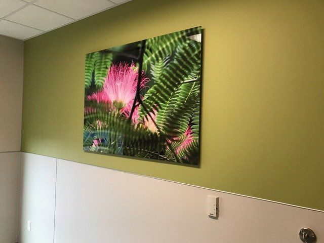 A painting of flowers and ferns is hanging on a wall in a bathroom.