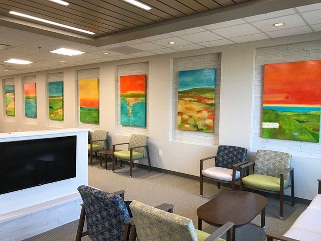 A waiting room with chairs and paintings on the wall