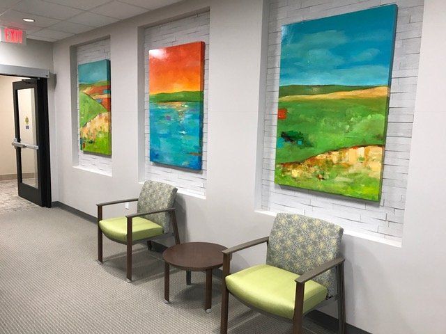 A hallway with chairs and paintings on the wall.