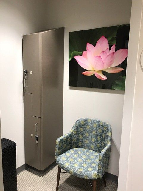 A room with a chair and a picture of a pink flower on the wall