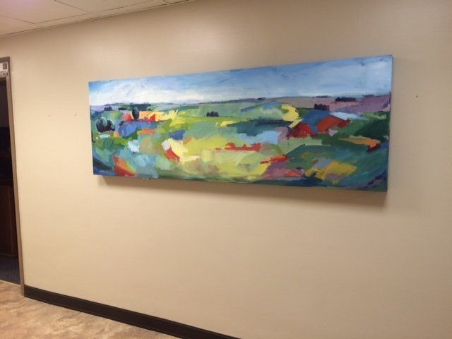 A large painting hangs on a wall in a hallway
