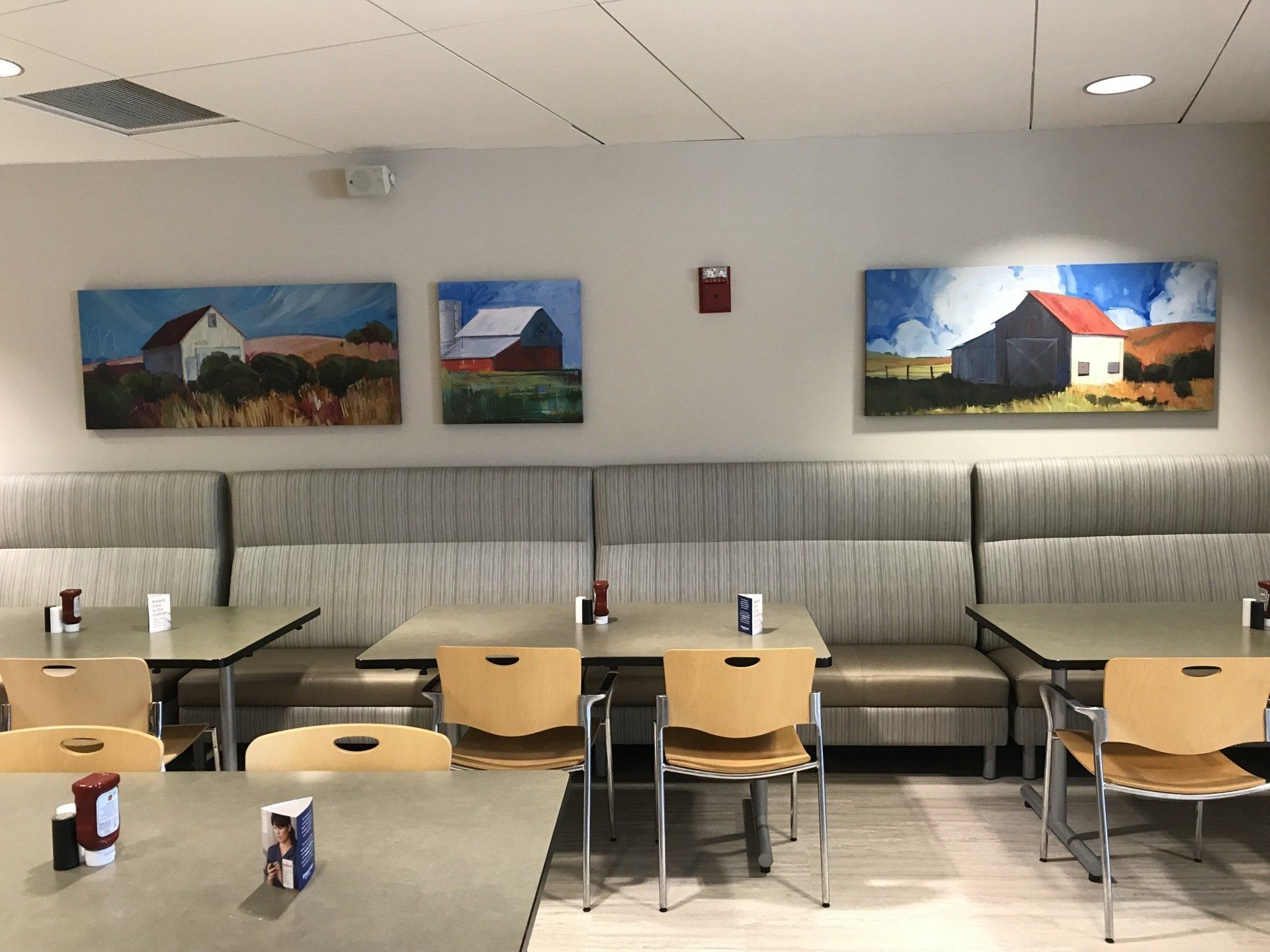 A restaurant with tables and chairs and paintings on the wall