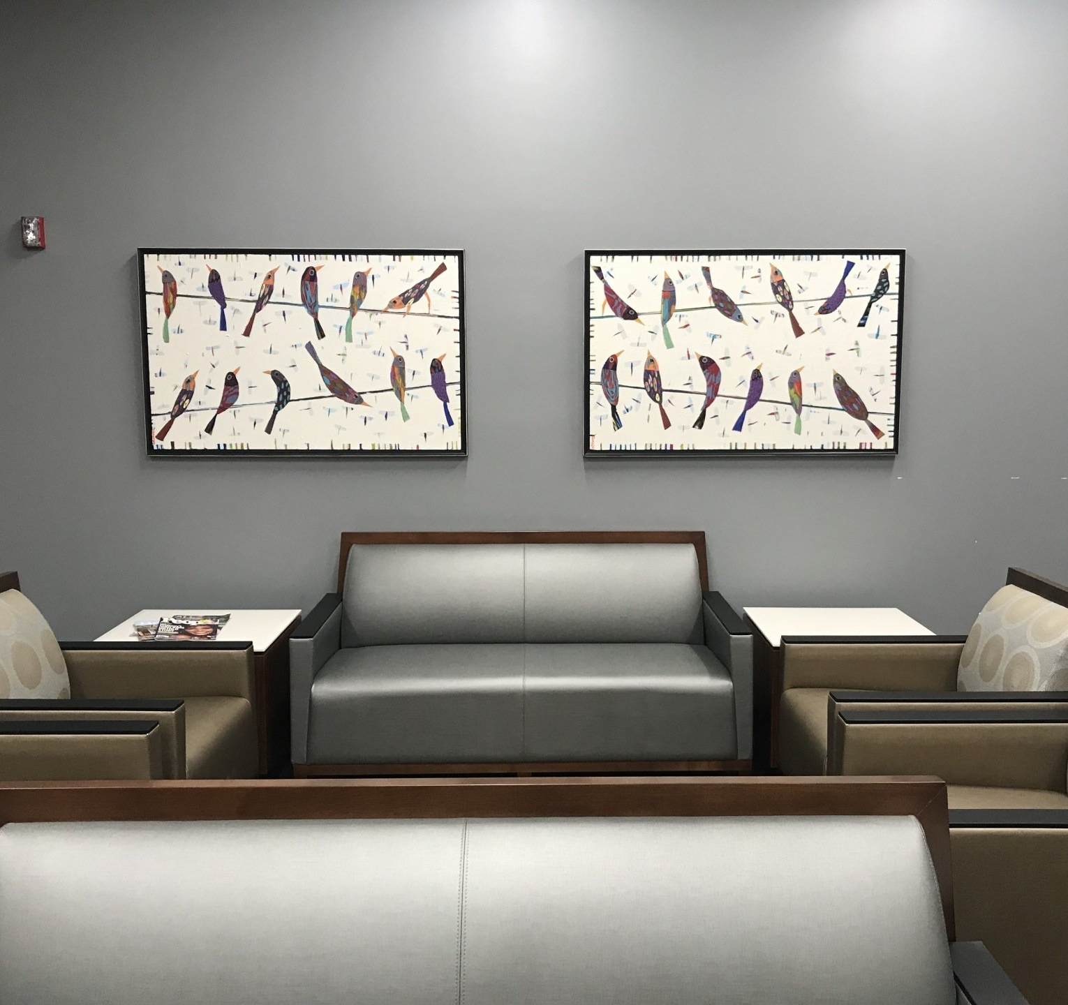 A waiting room with two paintings of birds on the wall