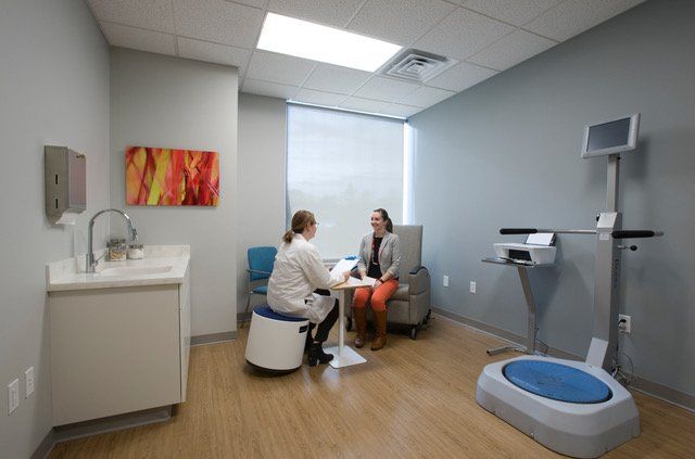 A woman is sitting at a table talking to a doctor in a room.