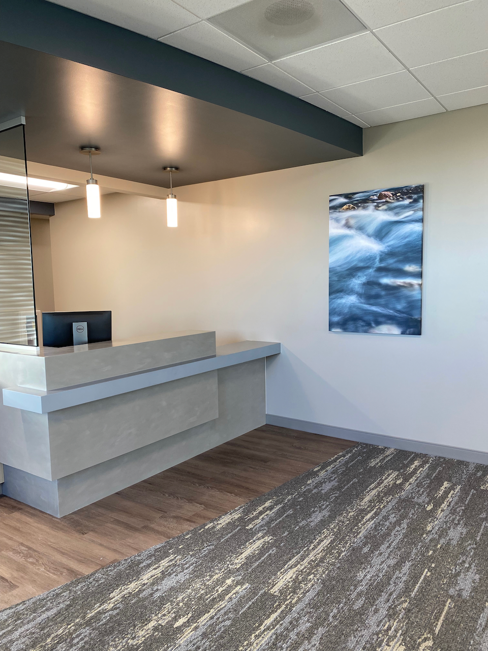 A reception area with a desk and a painting on the wall.