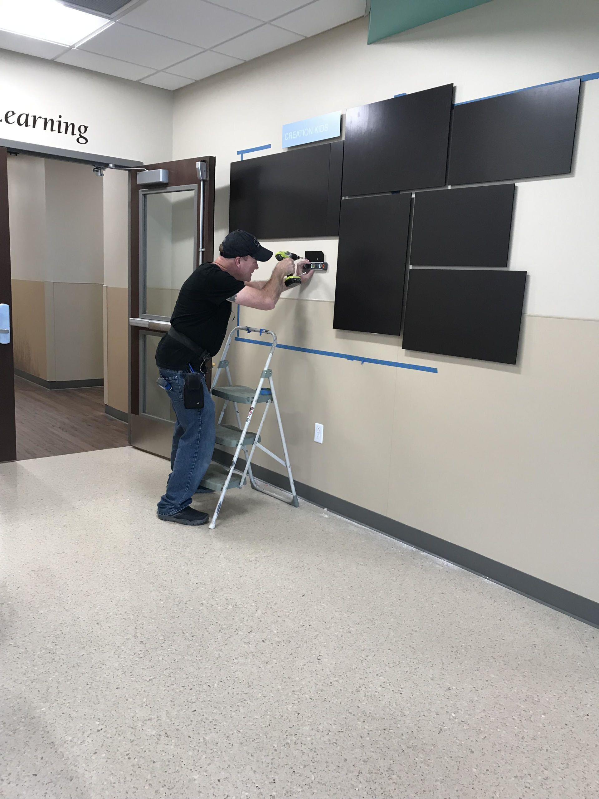 A man is standing on a ladder working on a wall.