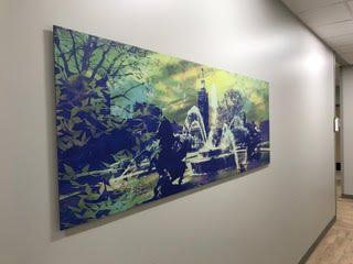 A large painting is hanging on a wall in a hallway.