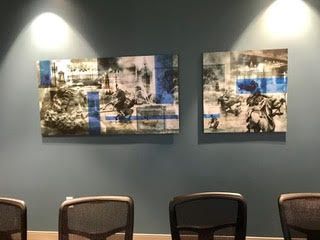 A conference room with a table and chairs and two paintings on the wall.